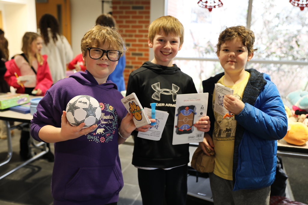 three students holding up the gifts they are getting