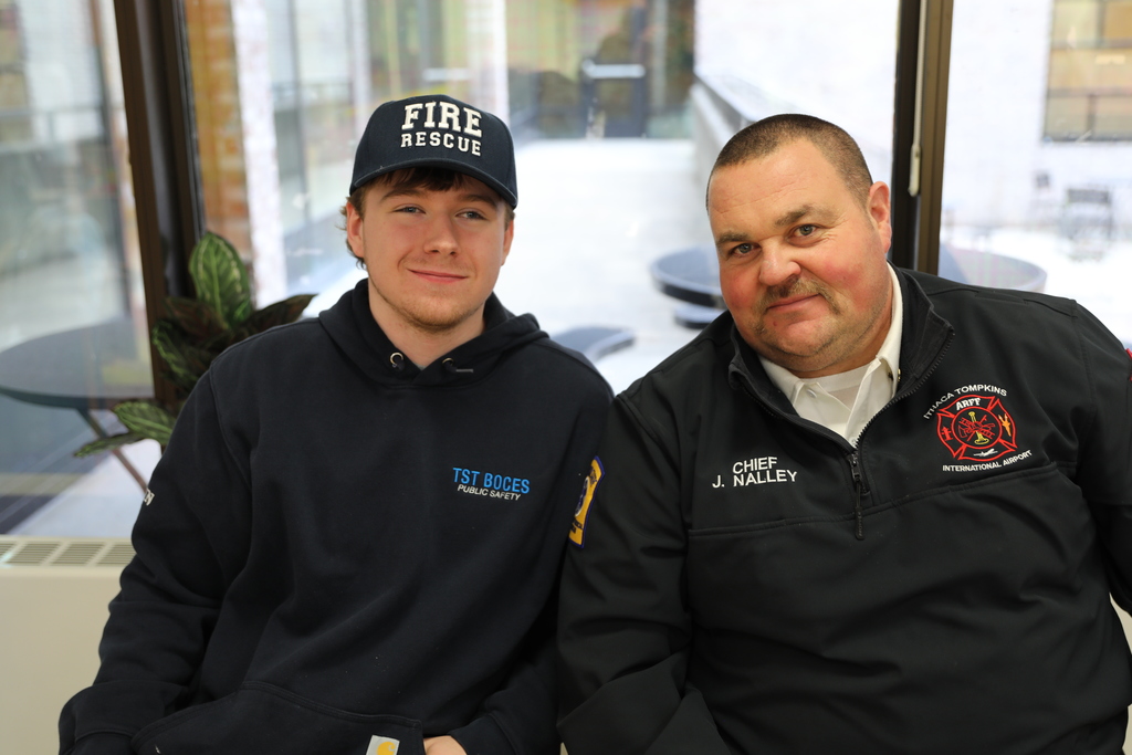 A student and the Fire Chief posing for a photo, smiling at camera