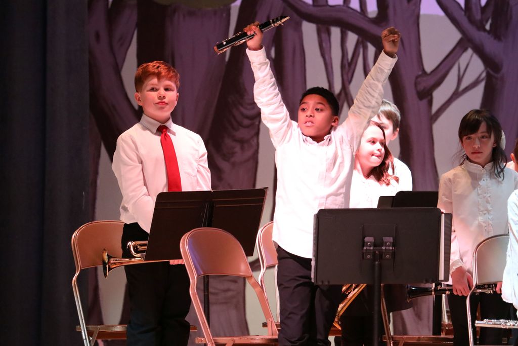 A student raising his arms in celebration after finishing the concert