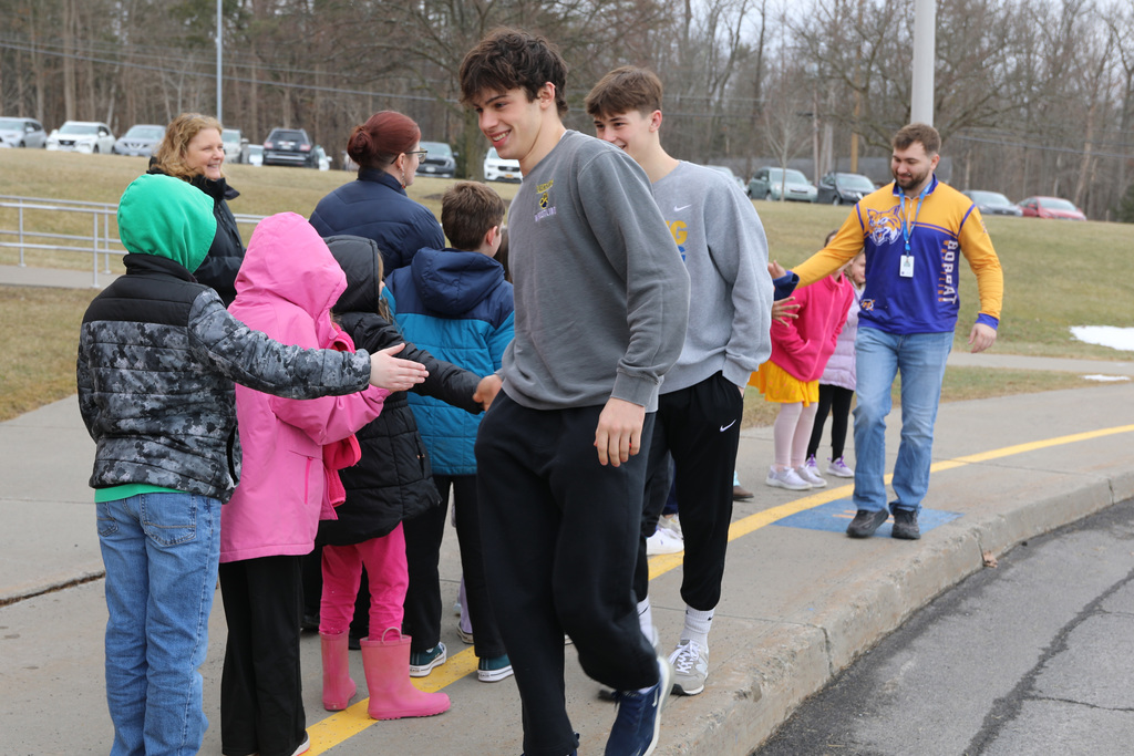 Wrestling students giving high fives to the elementary school students