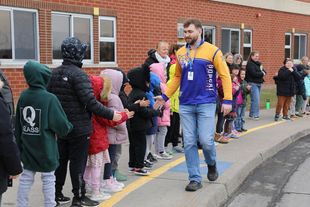 A wrestling student giving high fives to elementary school students