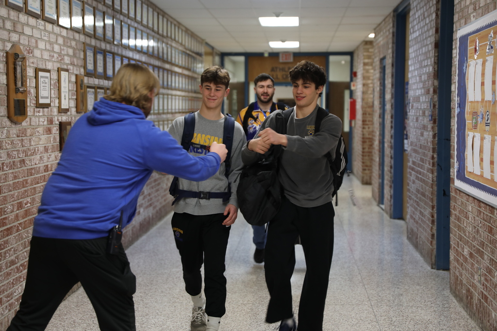 Two of the wrestling students getting fist pumps as they walk down the hall