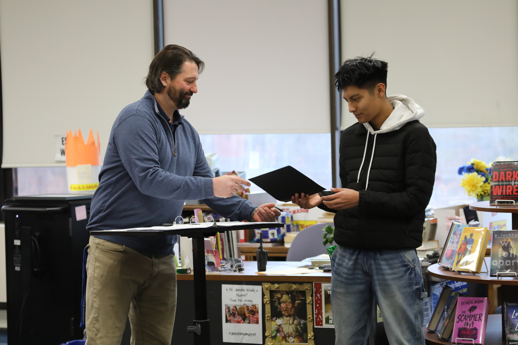 a teacher handing a student an award
