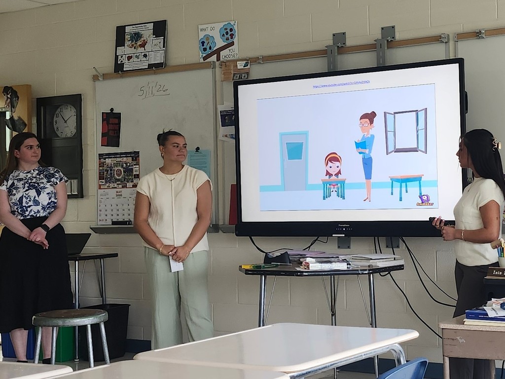 SUNY Cortland psychology students present to a high school economics class while displaying a slide with an illustration related to school psychology careers.