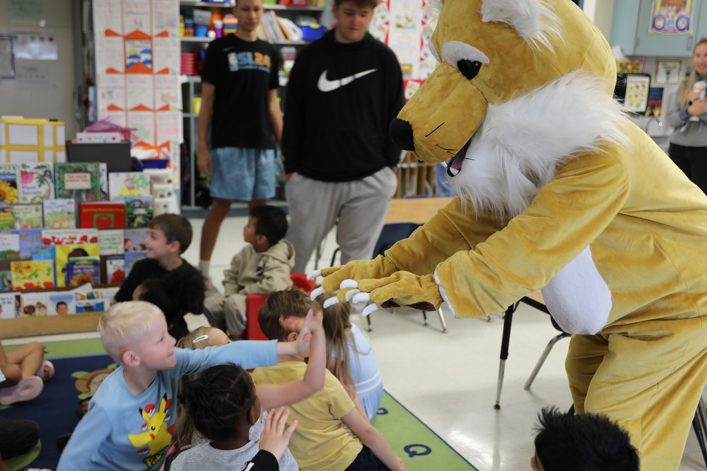 students in a class group giving high fives to the Bobcat