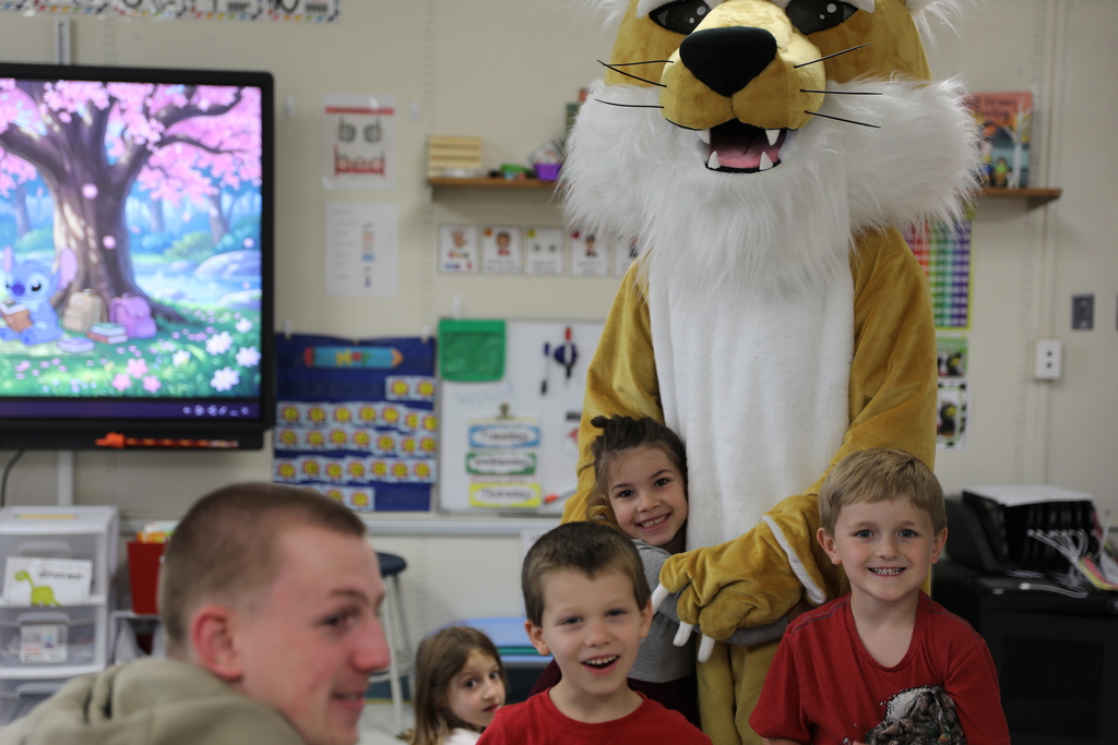 a few students smiling and another giving the Bobcat a hug