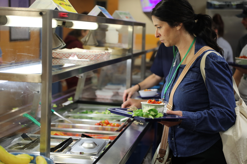 a line of people at the food serving bar getting their lunch