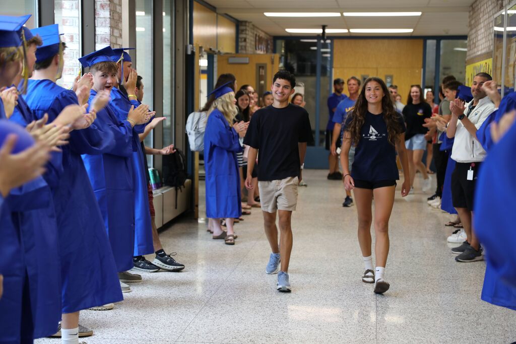two students walking down a hall while being cheered on