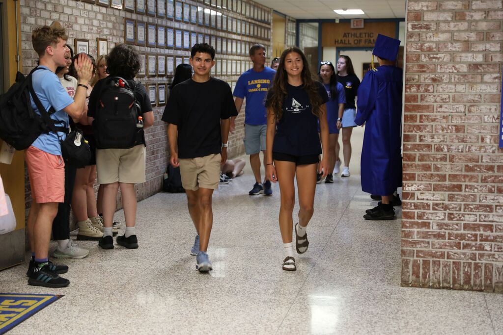 two students walking down the hall while being cheered on