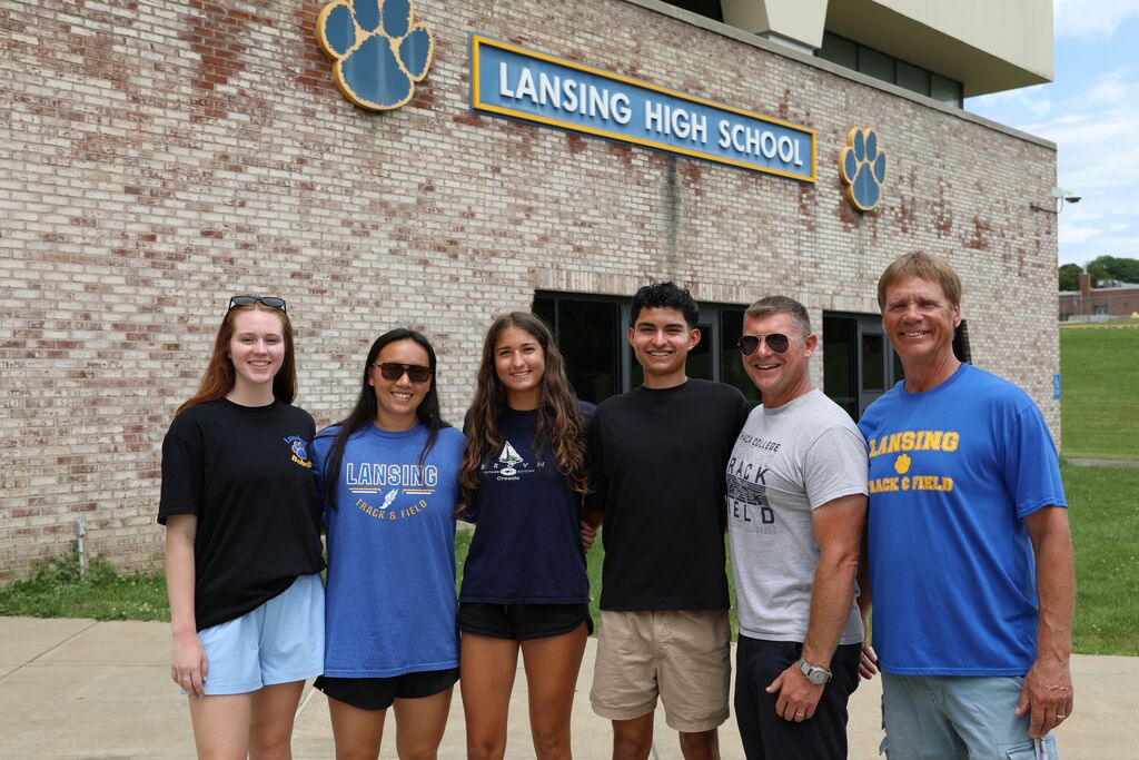 a group of six people posing for a photo in front of the Lansing High School