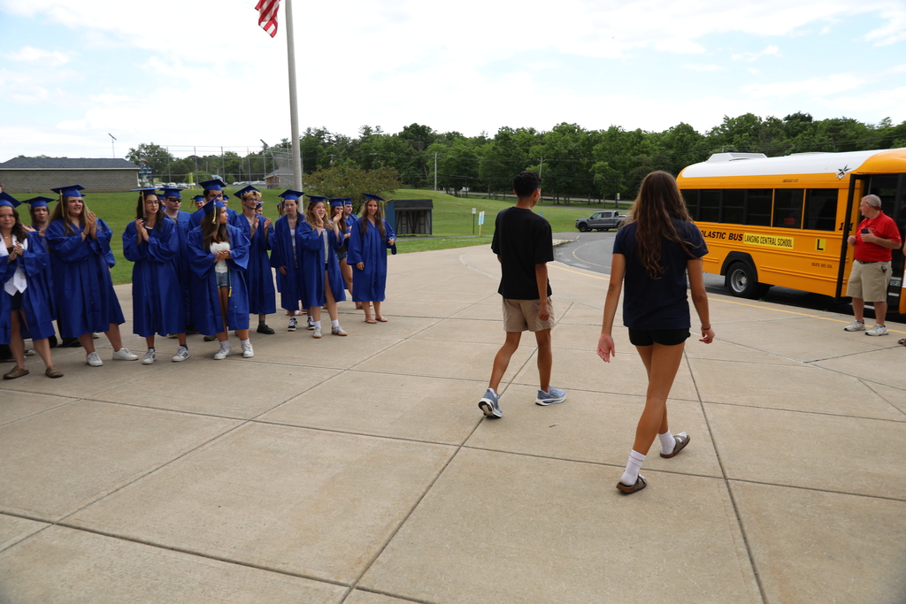 two students heading towards their ride as other graduating students cheer them on outside