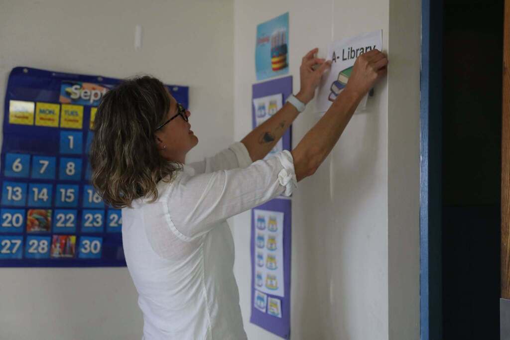 a teacher putting up a sign in her classroom