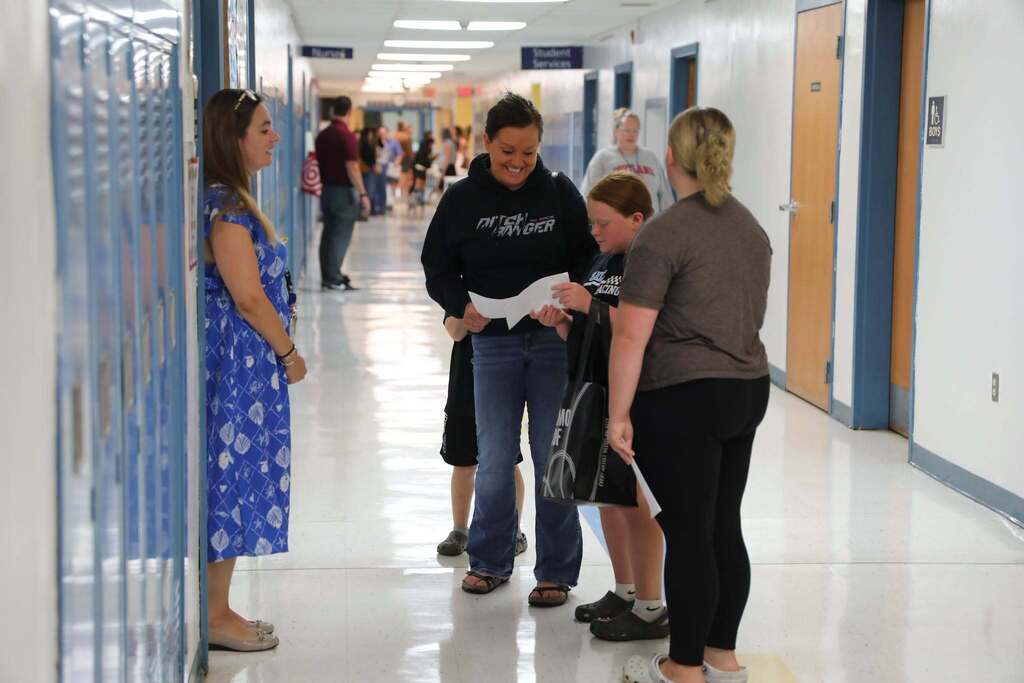 a teacher greeting a family in the hallway