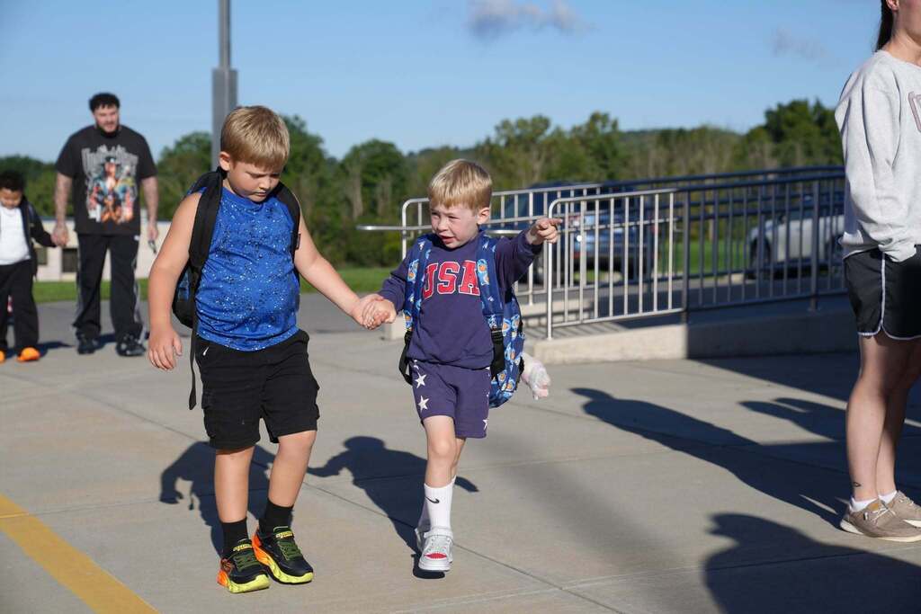 a student leading another student to the school by hand