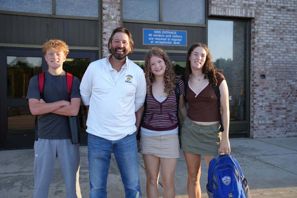 the principal posing with three students