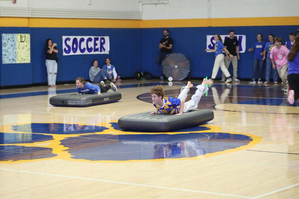 a student sliding on an inflatable mattress in a race