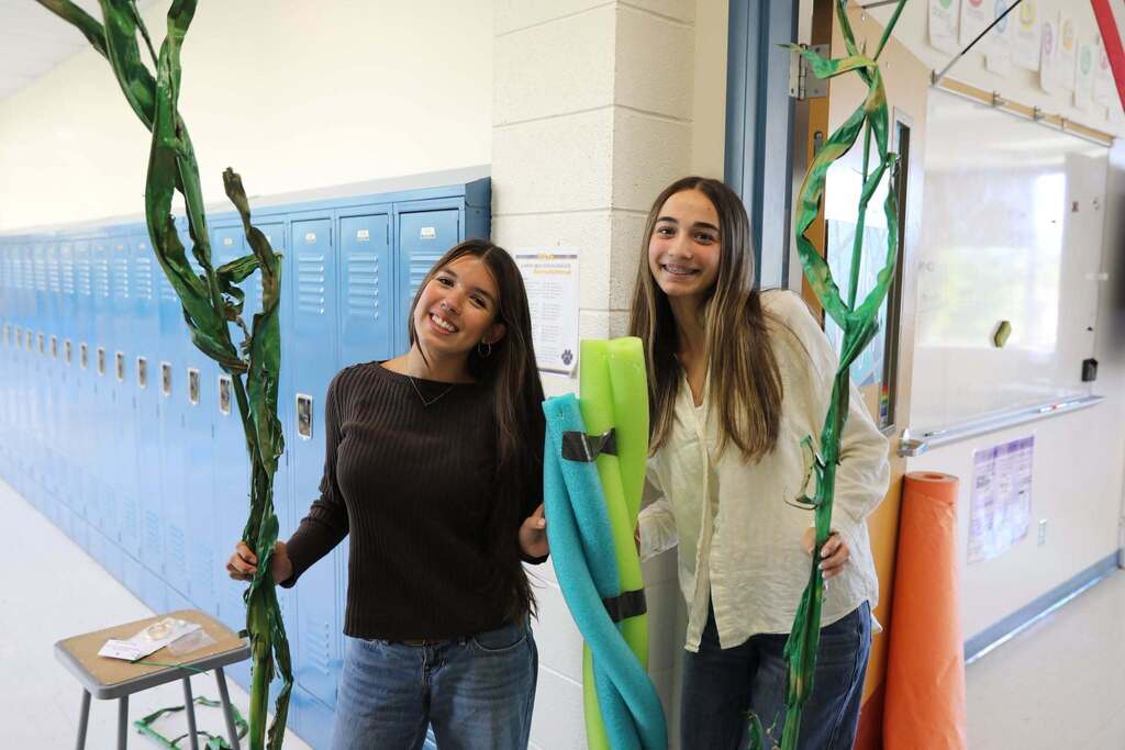 two students holding up hallways decorations
