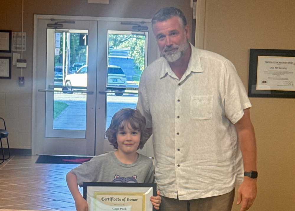 Student of the month with certificate and principal in board room