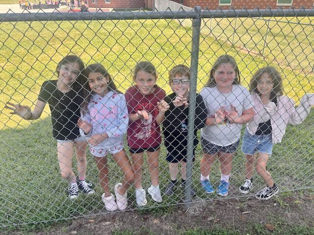 Students lined up at fence smiling