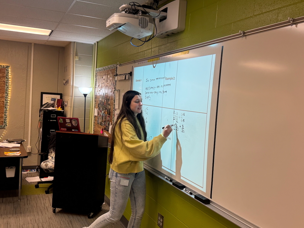 teacher writing a math problem on a white board