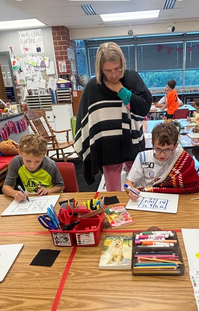 Students learning Math at desks with Teacher overseeing