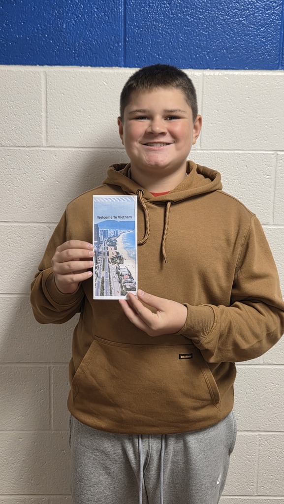8th Grade student holding travel brochure for class project