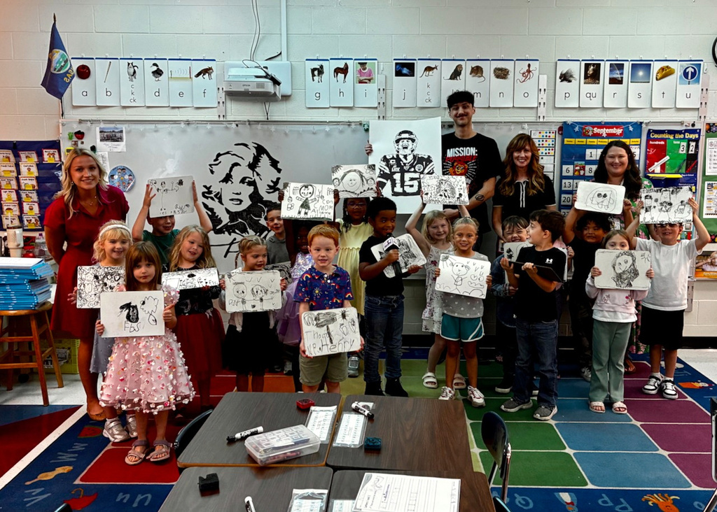 Students holding their artwork with custodian