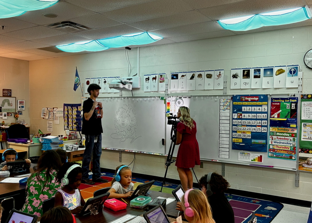Custodian being interviewed on camera while creating artwork on whiteboard
