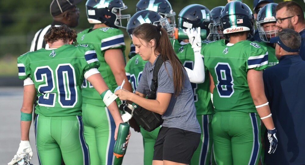 Female athletic trainer Jillian Sylvia tending to a Lapeer football player