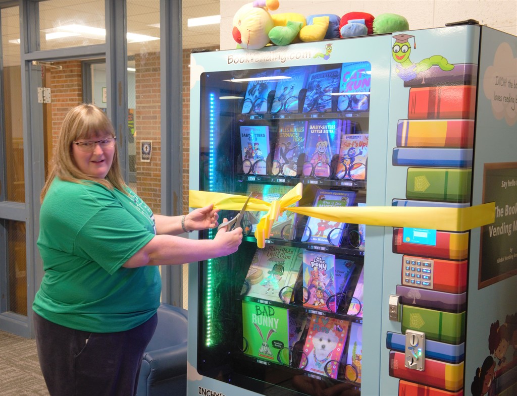 Traci Van Tine cutting the ribbon to open the book vending machine