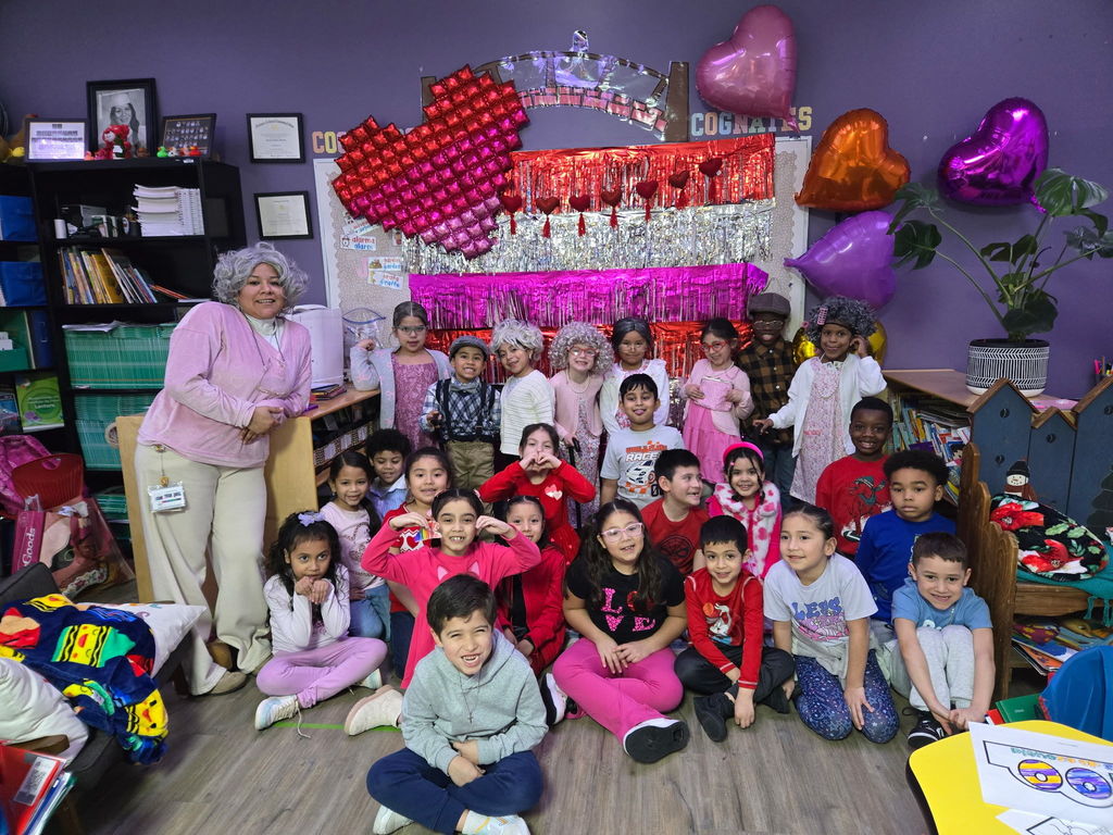 Students celebrating the 100th day of school, with a colorful Valentine's day background.