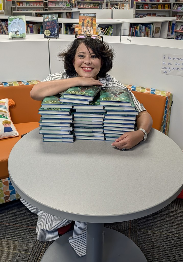 Author Erin Entrada Kelly posing with a stack of her books