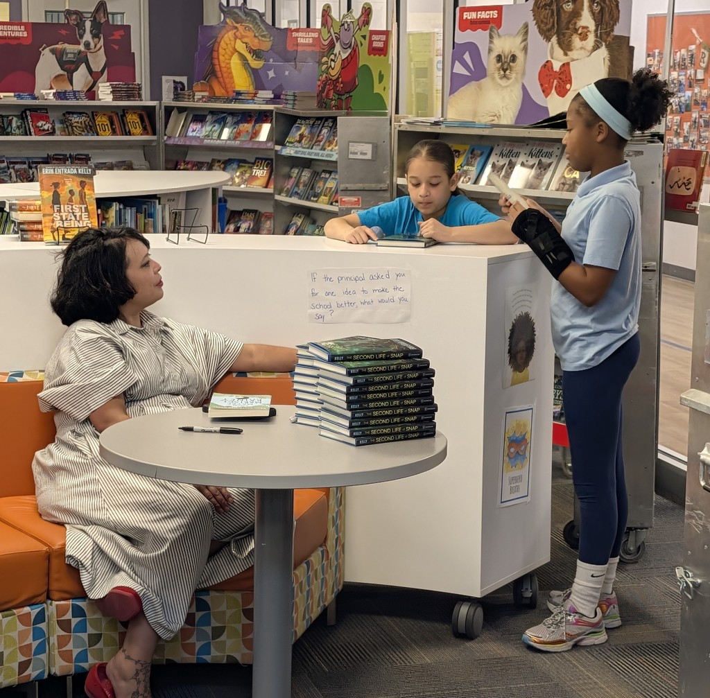 Author Erin Entrada Kelly talking to two students in the school library
