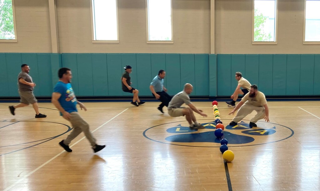 teachers playing dodge ball run for the ball