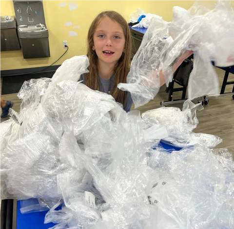 girl holding lots of clear plastic bags to make the weave art