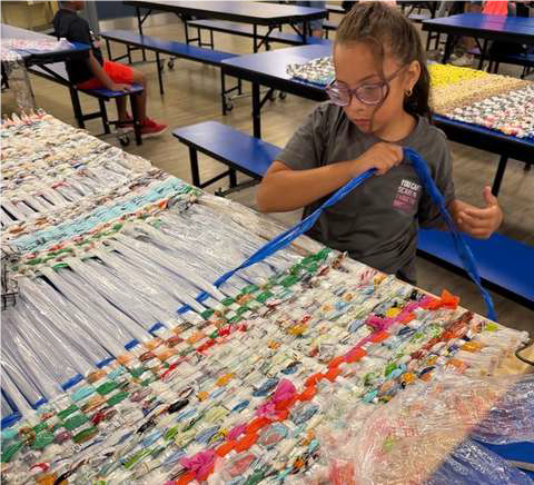 girl weaving artwork with plastic and ribbons 