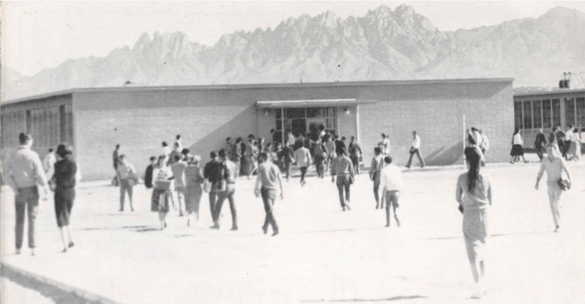 black and white photo of people walking toward a building