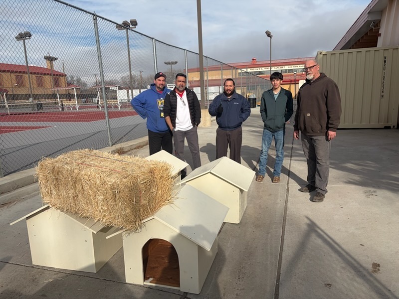 staff and student standing behind some dog houses