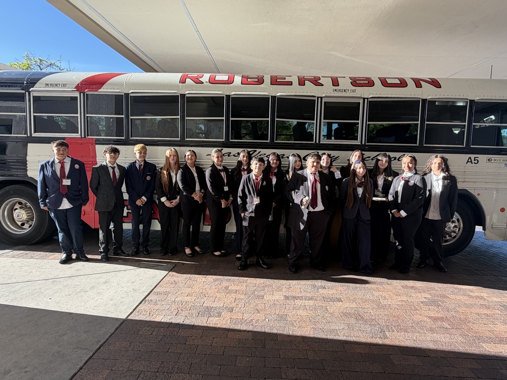 students posing in front of a bus