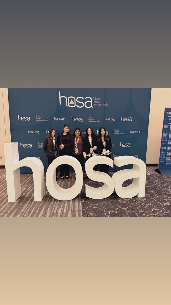 teacher and students smiling behind HOSA sign