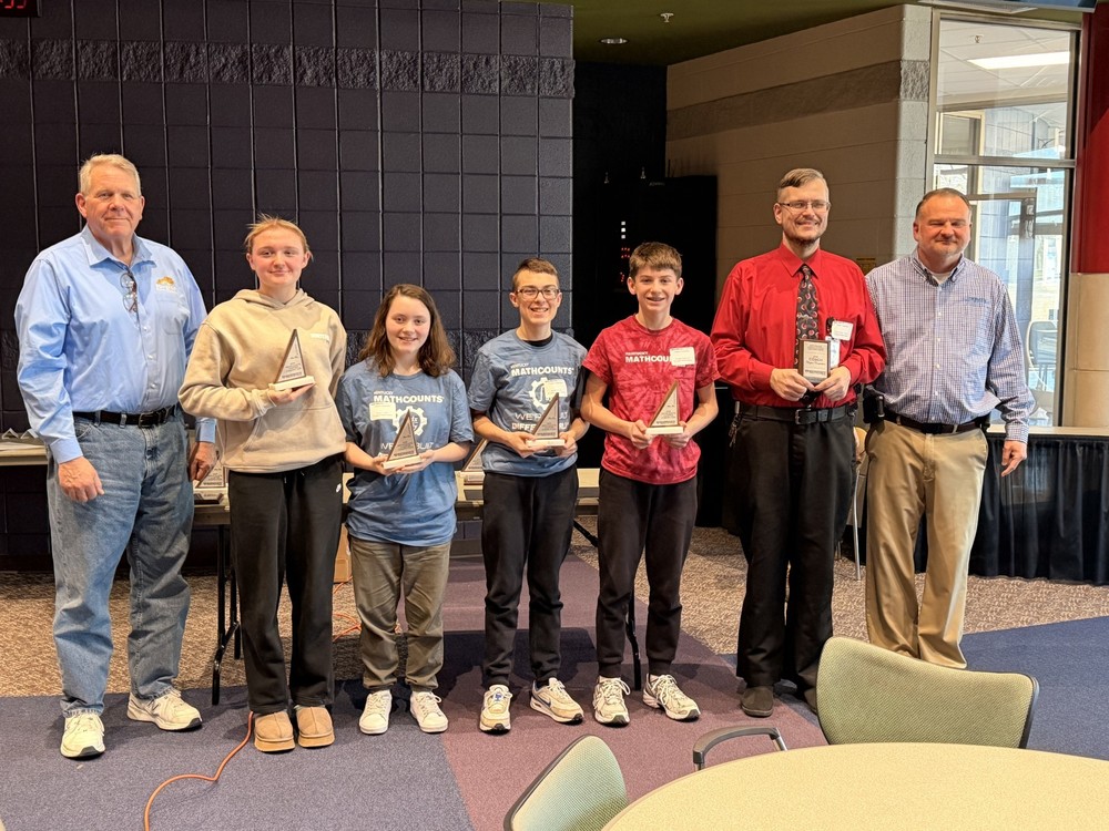 MathCounts team posing with coach Cody Moore and trophies