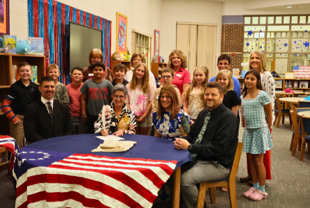 Proclamation Signing with students and DAR members in the background, Superintendent Griebel seated with guests signing proclamation