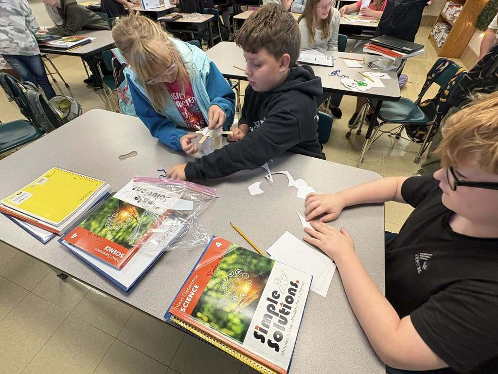One students handing two classmates pieces to make container 