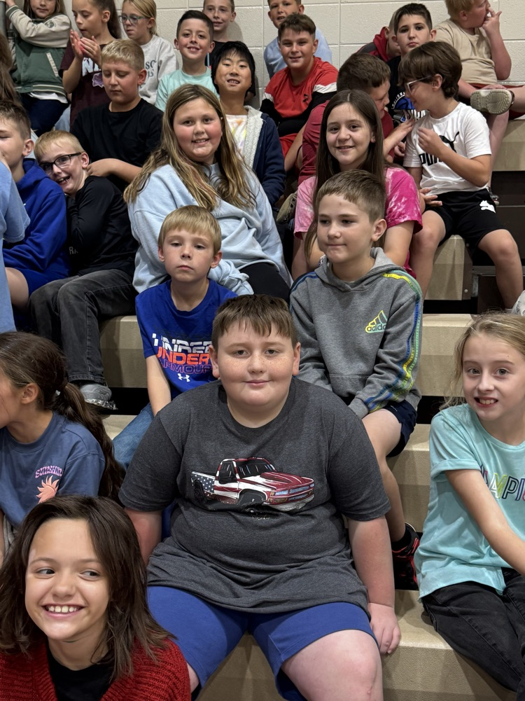 A large group of students smile while sitting in bleachers.