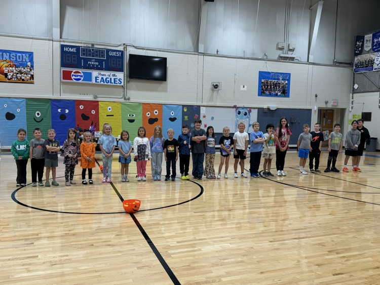 Smiling elementary school students stand in one line in the gym for their picture.