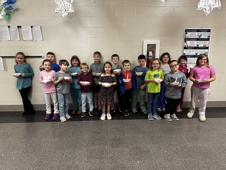 A group of several young students smiles for the camera while holding ice cream sundaes. 