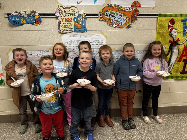 A group of young students smiles for the camera while holding ice cream sundaes. 