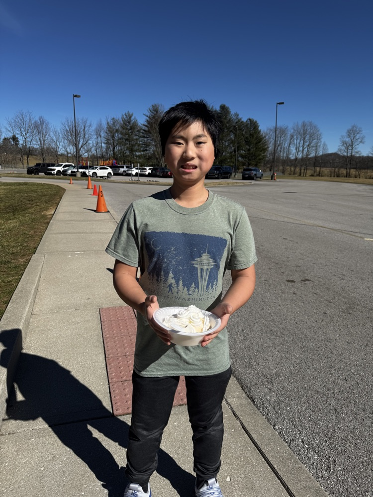 A young boy smiles for the camera while holding an ice cream sundae  