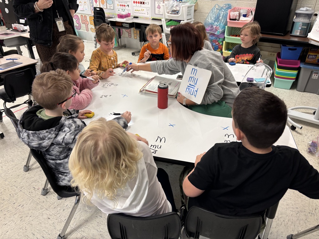 Elementary teacher working with students on learning the letter M
