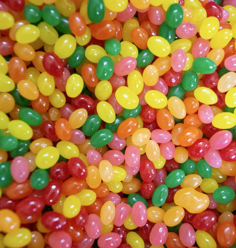 Pictured is a close-up of a large pile of pink, red, orange, yellow, and green jellybeans